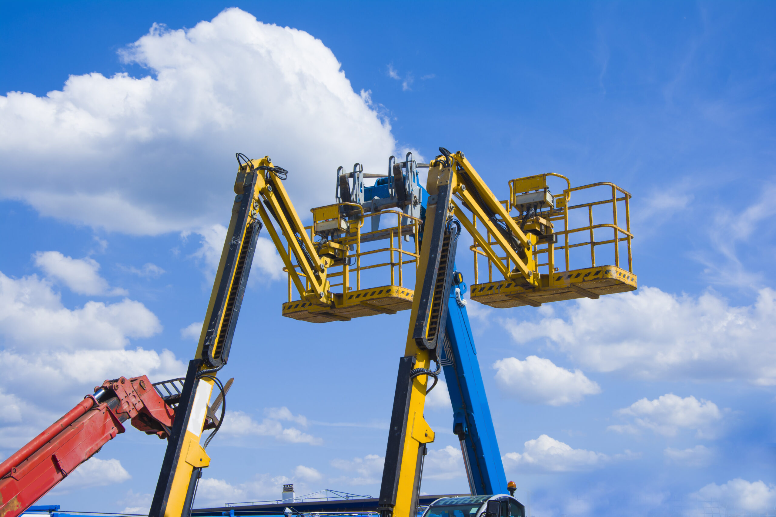 Lift buckets boom in the blue sky with clouds