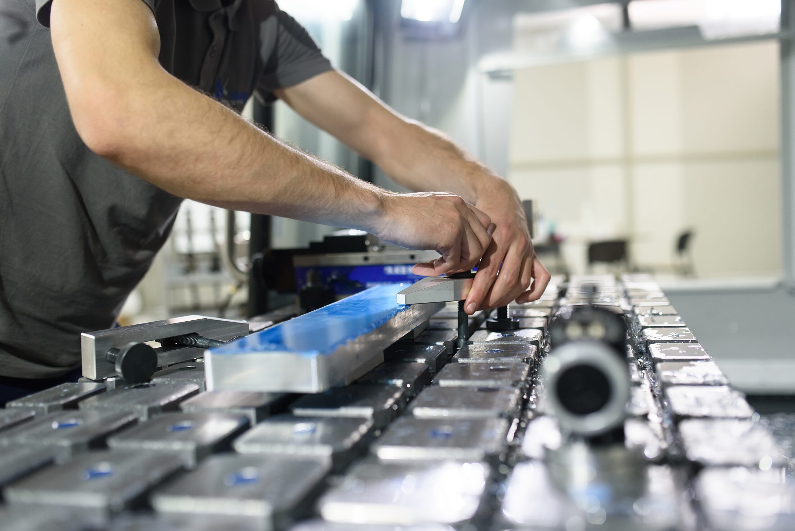 a man puts an aluminum piece on a cnc machine and prepares a processing machine
